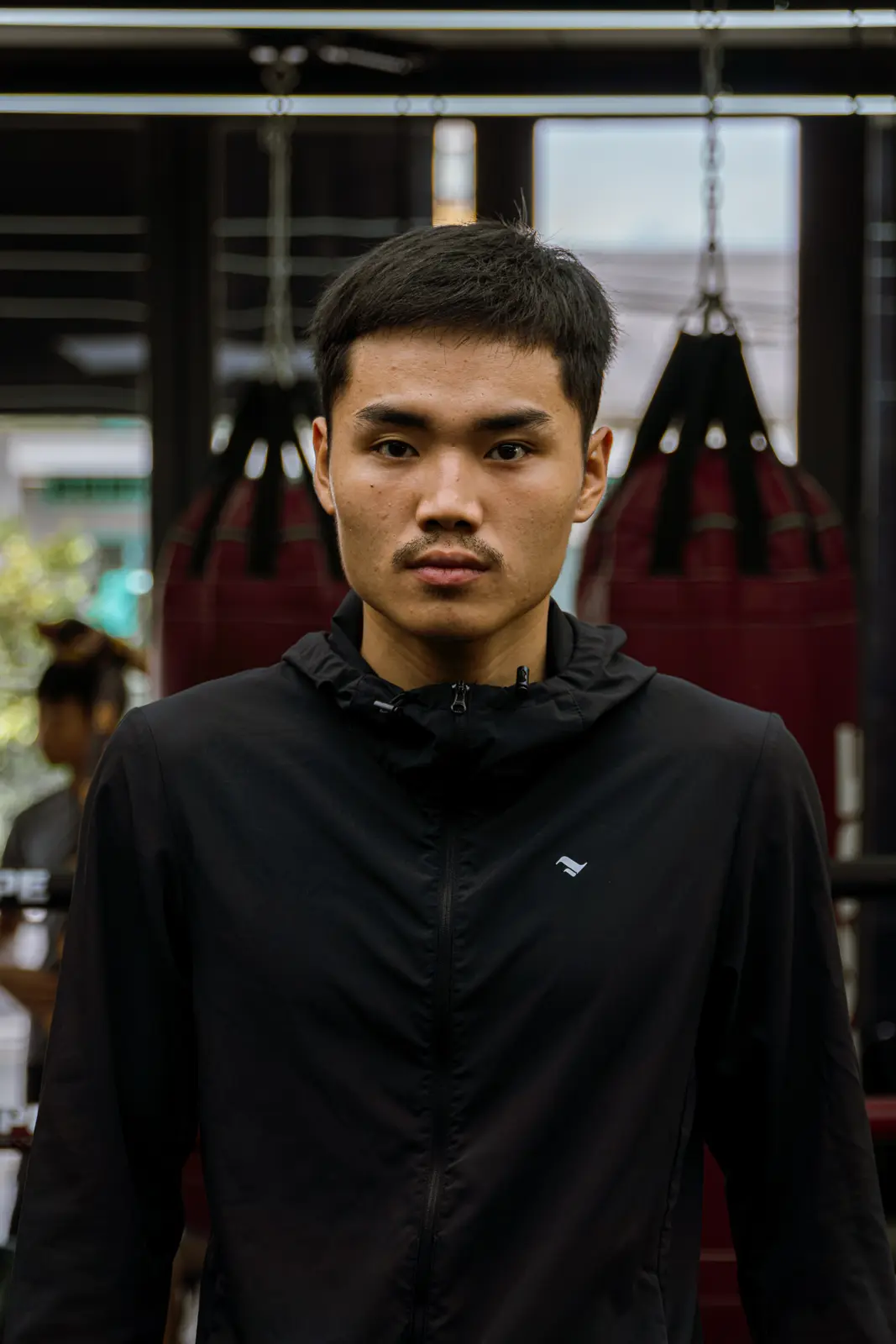 Coach Đạt mặc áo khoác đen, đứng trước bao cát tại HYPE
