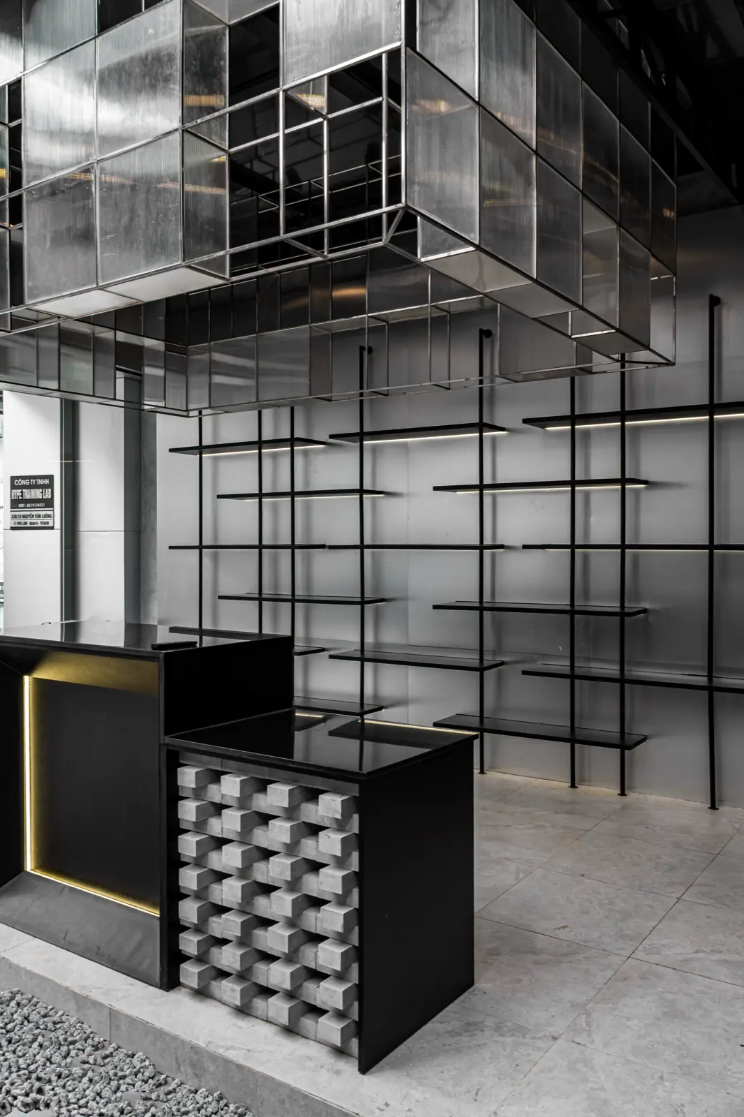 Khu lounge tại HYPE — quầy lễ tân và kệ kim loại nhìn dọc