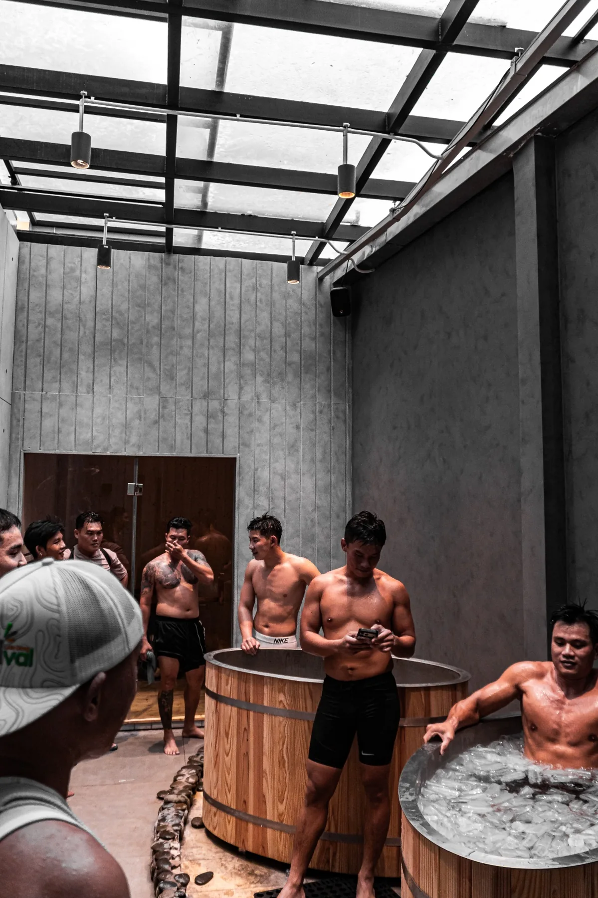 Khu Recovery — nhóm học viên đứng quanh bồn gỗ, một người ngâm bồn đá