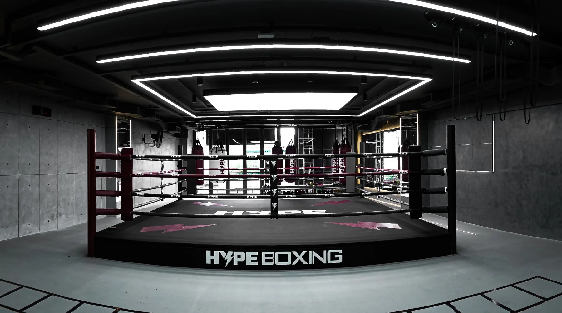 Sàn đài HYPE BOXING với cột góc đỏ, phía sau là dãy bao cát treo